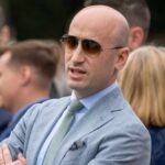 Backlash EXPLODES Over Trump Advisor’s Hypocrisy Man in a light suit and sunglasses speaking at an outdoor event