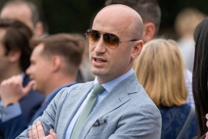 shutterstock_2616119063.jpg Man in a light suit and sunglasses speaking at an outdoor event