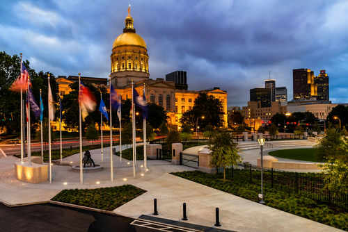 Capitol building with flags at dusk in cityscape