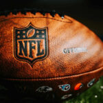 Raiders’ Mega Deal Rocks NFL Close-up of an NFL football on grass.
