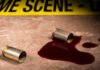 Bullet casings and blood on a surface near a crime scene tape