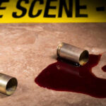 Bullet casings and blood on a surface near a crime scene tape