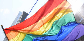 A vibrant rainbow flag waving against a city backdrop