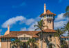 Historic mansion with a tower surrounded by palm trees under a blue sky