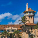 Shock Win in Mar-a-Lago’s Shadow: GOP Ousted Historic mansion with a tower surrounded by palm trees under a blue sky
