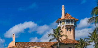 Historic mansion with a tower surrounded by palm trees under a blue sky