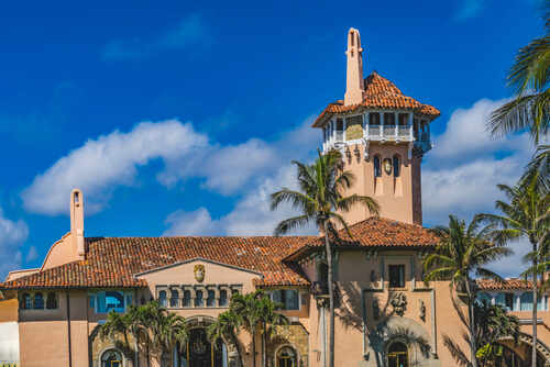 shutterstock_1998622337.jpg Historic mansion with a tower surrounded by palm trees under a blue sky