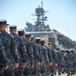 Trump’s Bold Promise: Convoys Through Hormuz Navy personnel marching in formation towards a ship
