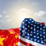 U.S.-China Relations in Crisis: What Comes Next? Crumpled flags of the USA and China against a cloudy sky
