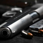 Governor’s Gun Laws: Rights Under Siege? Close-up of a handgun and ammunition on a dark background