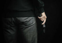A person holding a gun with a dark background