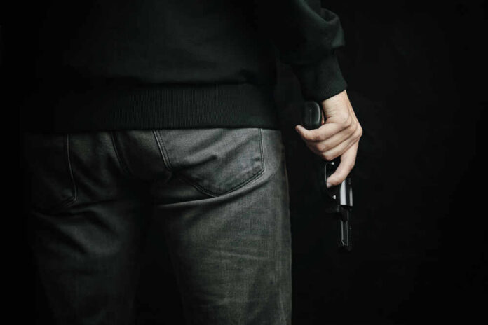 A person holding a gun with a dark background