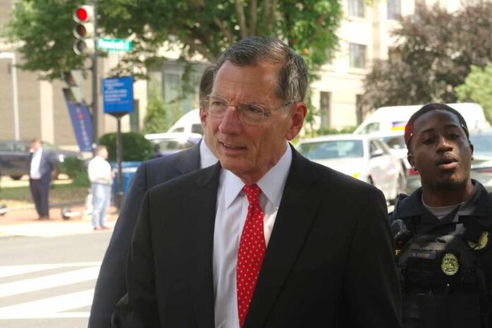 A man in a suit with a red tie walking outdoors, accompanied by a police officer