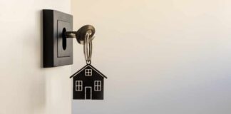 A key with a house-shaped keychain inserted into a door lock