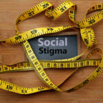 Outrage Erupts: Neighbor’s Vile Note Crosses Line A measuring tape surrounding a sign that reads 'Social Stigma'