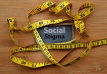 A measuring tape surrounding a sign that reads 'Social Stigma'
