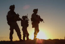 Silhouetted soldiers standing against a sunset