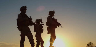 Silhouetted soldiers standing against a sunset