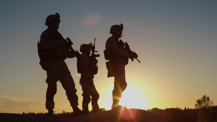 shutterstock_676001056.jpg Silhouetted soldiers standing against a sunset