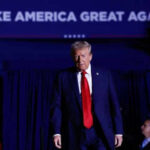 Person in red tie at rally under blue banner