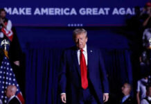 Person in red tie at rally under blue banner