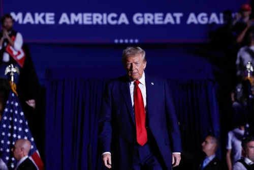 trump-maga2543862833 Person in red tie at rally under blue banner