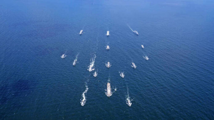 Aerial view of multiple naval ships operating in the ocean