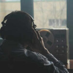 Person listening to audio reel beside window