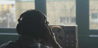 Person listening to audio reel beside window