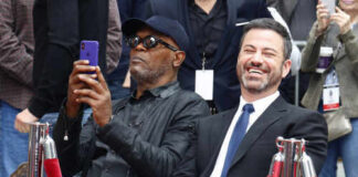 Two men sitting together at a celebrity event, one taking a photo