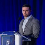 Shapiro’s Explosive Call: Target Kharg Island? A man in a gray suit speaking at a podium during a conference