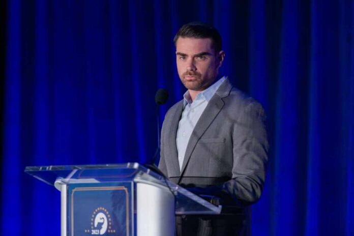 shutterstock_2381827657.jpg A man in a gray suit speaking at a podium during a conference