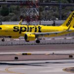 Spirit Airlines COLLAPSES – $500M Bailout Fails! A yellow Spirit Airlines airplane landing on an airport runway