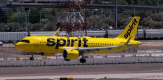 A yellow Spirit Airlines airplane landing on an airport runway