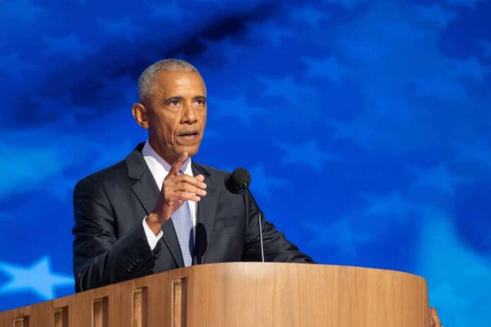 shutterstock_2507620031.jpg A man in a suit delivering a speech at a podium with a blue starry background
