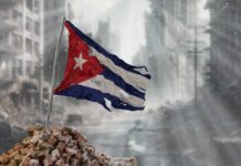 Invasion Chatter Spikes — Proof Still Missing Worn Cuban flag standing on rubble in a desolate urban environment