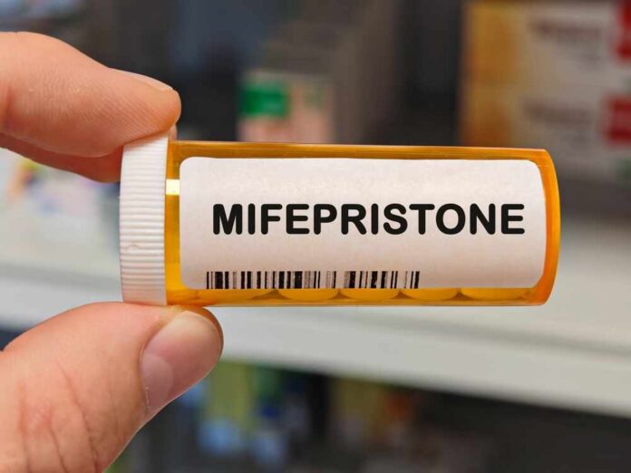 shutterstock_2707972423.jpg A hand holding a prescription bottle labeled Mifepristone