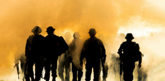 Silhouettes of soldiers walking through smoke at sunset