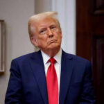 Trump’s Beijing Moves: What’s He Not Telling? Person in suit and red tie standing indoors