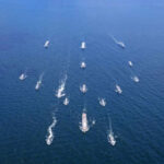 Aerial view of multiple naval ships operating in the ocean