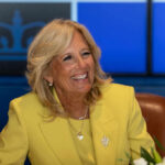 Smiling woman in a yellow blazer at a meeting table