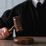A judge holding a gavel above a wooden block