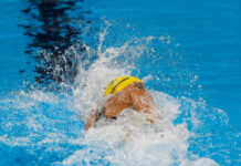 Swimmer in yellow cap racing in pool