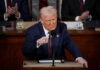 Trump’s “Hall Of Shame” Targets Influencers Man in suit speaking at a podium during an event