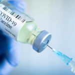 Washington Reopens The COVID Vaccine Debate Gloved hand holding COVID19 vaccine vial and syringe