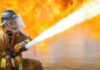 Firefighter spraying water to extinguish large blaze