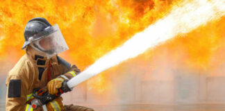 Firefighter spraying water to extinguish large blaze