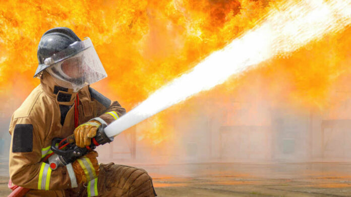 Firefighter spraying water to extinguish large blaze