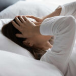 Woman lying in bed with hands on head