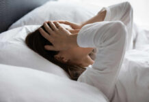 Woman lying in bed with hands on head